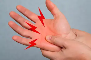 Close-up image of a person pressing their thumb into the palm of their hand, with red lightning bolts illustrating pain from compression or entrapment neuropathy